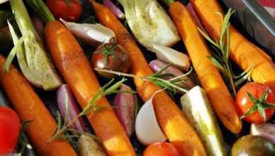 Colorful vegetables ready for baking, featuring carrots, tomatoes, and herbs.