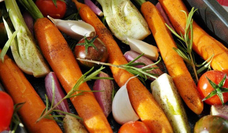 Colorful vegetables ready for baking, featuring carrots, tomatoes, and herbs.